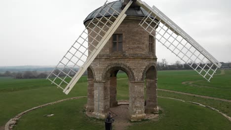 Aerial pedestal shot of a photographer taking a picture of a historic windmill.