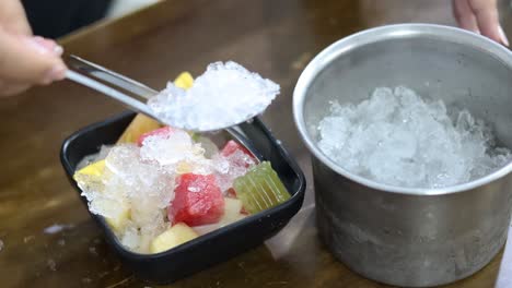 adding ice to a fruit dessert bowl