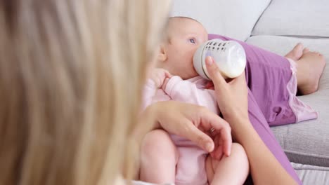 Baby-lying-on-sofa-getting-bottle-feed-by-his-mother