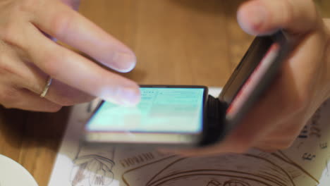 man surfing internet on cell in cafe