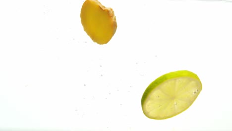 limón verde y jengibre cayeron al agua, aislados en fondo blanco