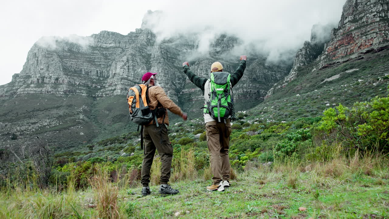 두 남자가 산에서 하이킹을 하고 있다.
