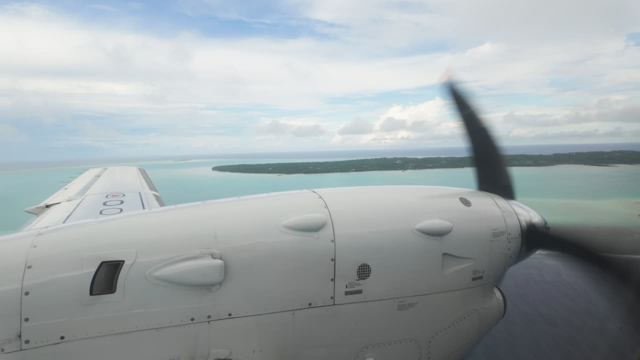 Travel destination, slow motion view from inside airplane looking out at wing and propellor over tropical islands