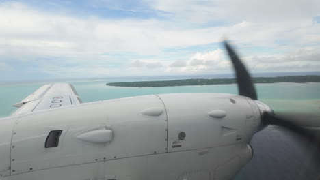 travel destination, slow motion view from inside airplane looking out at wing and propellor over tropical islands