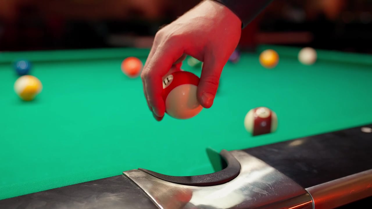 Close-Up of Hand Placing Striped Pool Ball on Green Table