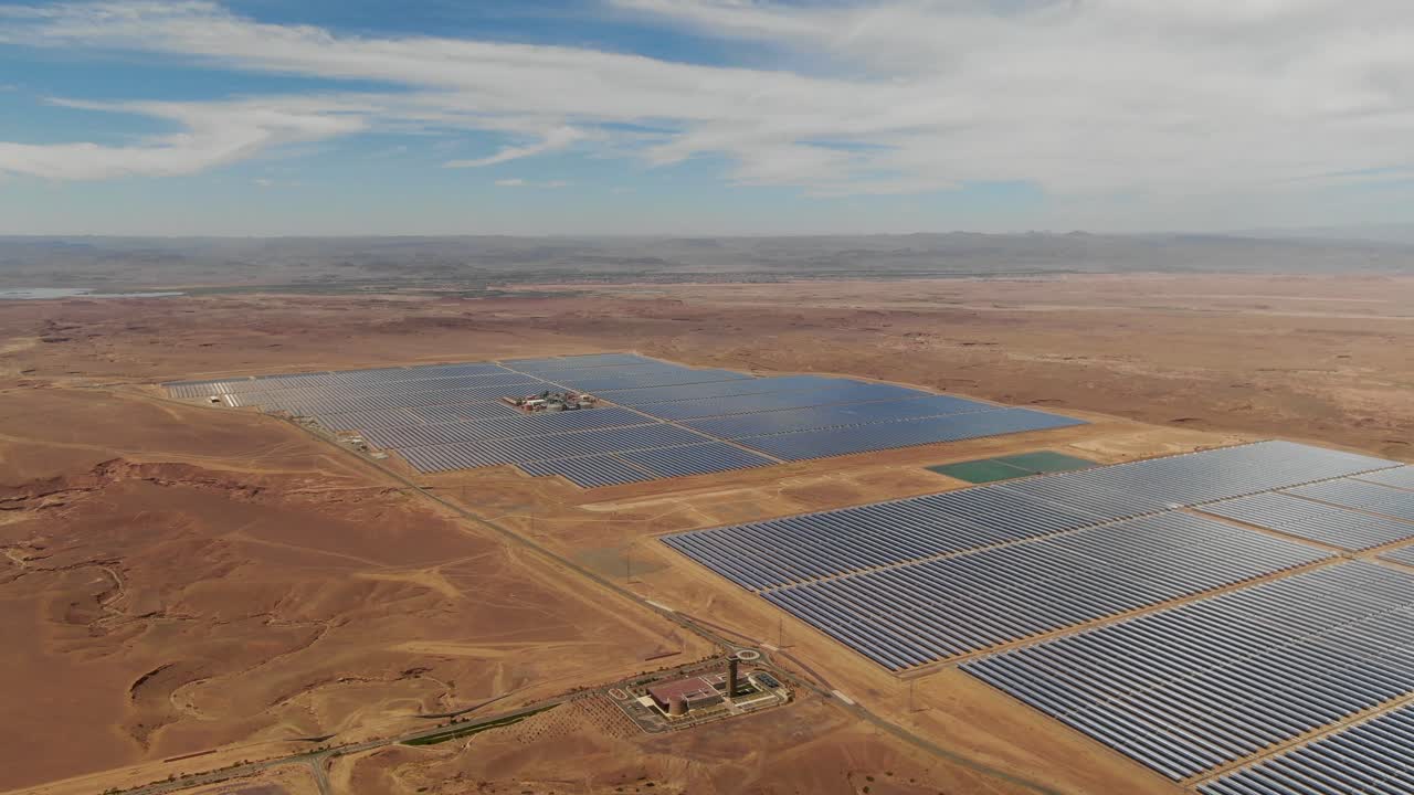 Luftfoto af solcelleparker ved solkraftværket Ouarzazate i Marokko, der fremhæver infrastruktur for vedvarende energi i et ørkenlandskab.