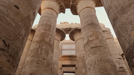 majestic view of the towering stone columns inside the karnak temple complex in luxor, egypt. the pillars are adorned with intricate hieroglyphic carvings and symbols from ancient egyptian history.