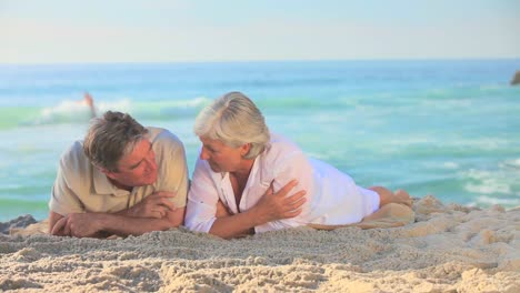 Elderly-couple-lying-on-the-sand