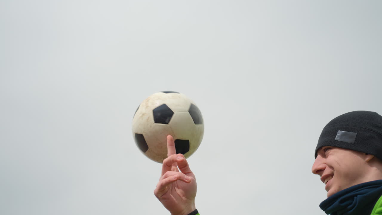 Diversión con el balón de fútbol, un hombre hace malabares con él fácilmente, jugador casual realizando trucos de fútbol freestyle al aire libre, un individuo muestra hábiles trucos con el balón de fútbol con un cielo nublado de fondo