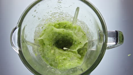 verduras jugosas mezcladas en un mezclador girando dentro del cuenco en primer plano en súper cámara lenta