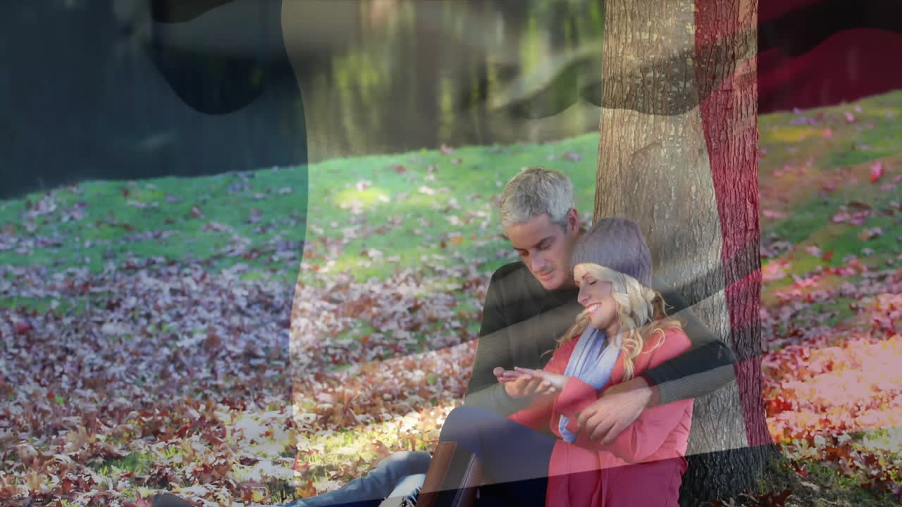 sentados bajo un árbol con hojas de otoño, pareja rodeada por la animación de la bandera de bélgica