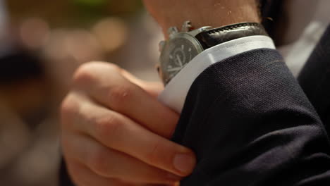 hombre rico abotonando la manga de la camisa bajo el arco. hombre manos con reloj de muñeca