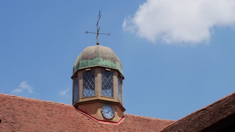 static shot of old clock and compass over cottage building roof