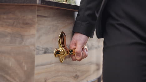 Coffin,-hands-and-pallbearer-walking-at-cemetery