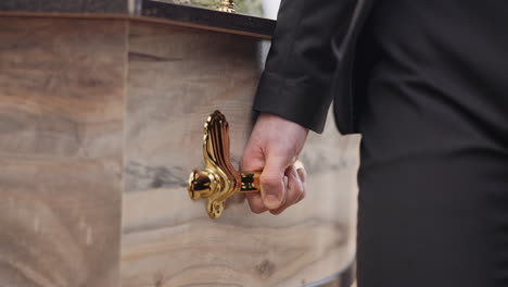 coffin, hands and pallbearer walking at cemetery