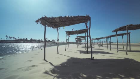 Strandhütten-An-Einem-Sonnigen-Tag-In-Brasilien-Mit-Kitesurfern,-Die-An-Der-Küste-Surfen