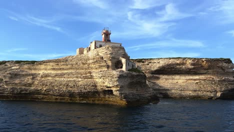 amazing low angle view of famous madonnetta lighthouse perched on cliff in southern corsica island seen from tour boat