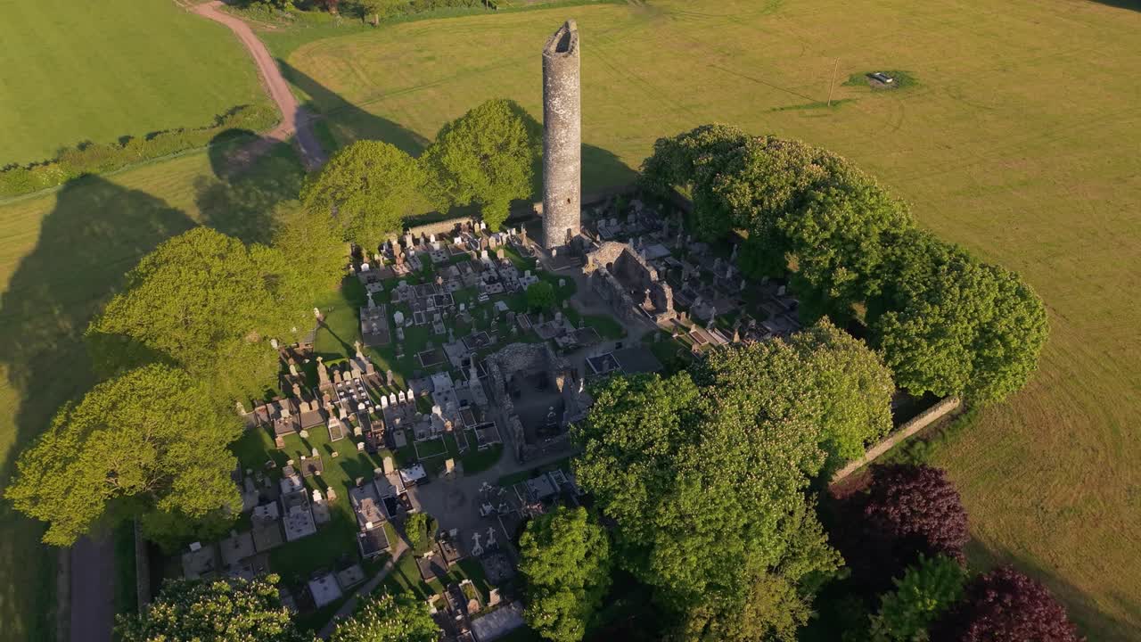 Aerial View of Ancient Ruins, Graveyard, And Round Tower Of Monasterboice On Sunny Day In County Louth, Ireland. pullback shot