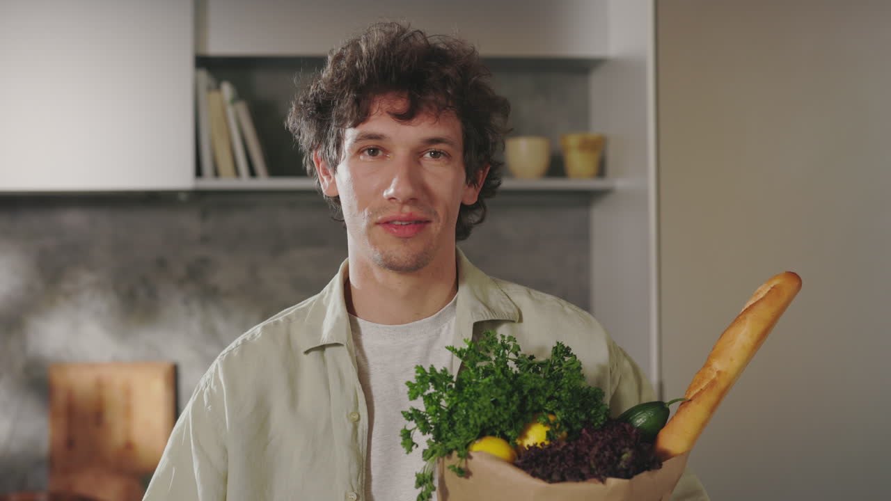 Man holding a grocery bag in a kitchen