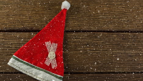 falling snow with christmas santa hat on wood