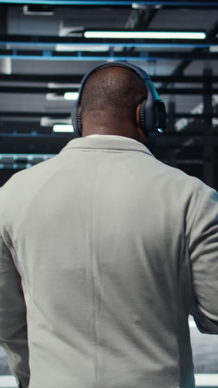 Vertical video Admin walking in data center, listening music while doing inspection