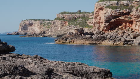 Turquoise-waters-of-Mallorca,-Spain,-encircled-by-a-rock-formation