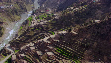 Aerial-view-of-The-roof-tops-of-the-Kashmir-with-simple-lifestyle-of,-simple-houses,-with-wood-borders,-thatched-roofs-and-small-cottages,-A-curvy-road-with-river-making-beautiful-view