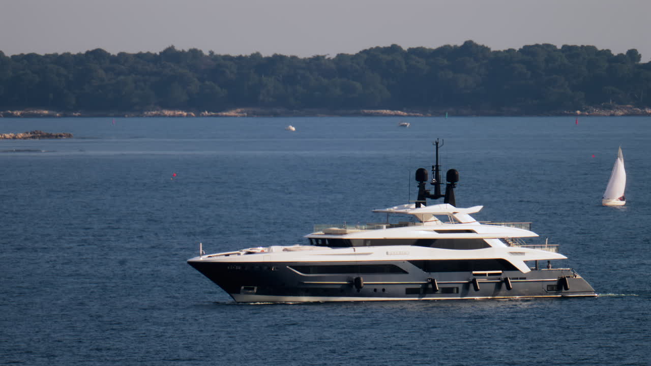 A white boat moving on the sea with trees on the background in the French Riviera