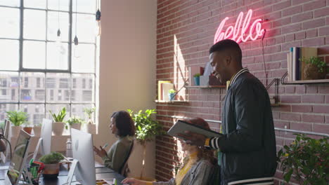 young african american businesman team leader enjoying management career checking colleagues working using tablet computer confident manager walking in diverse office workplace