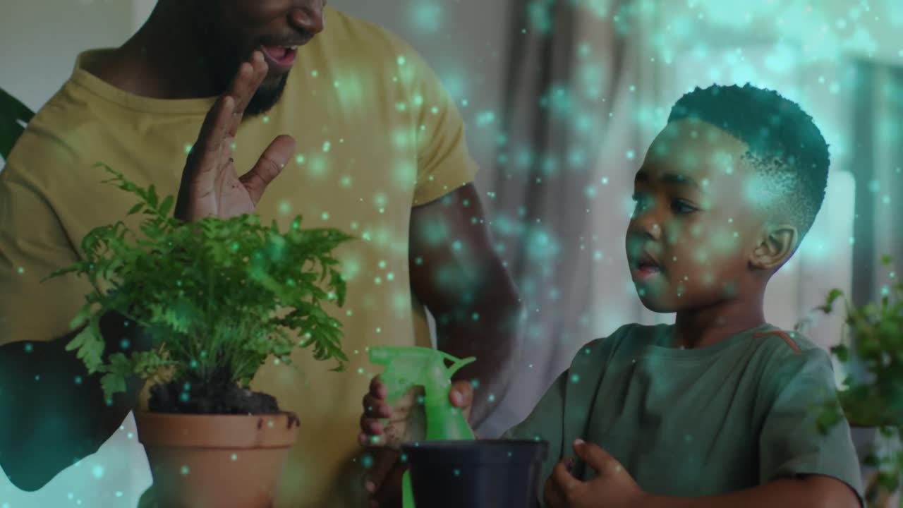 Animation of lights over happy african american father and son watering plants and clapping hands