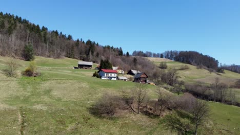 aerial approaching rustic houses on hill against blue sky on a sunny day, lasko, slovenia