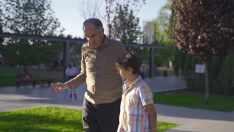 abuelo y nieto caminando al aire libre.