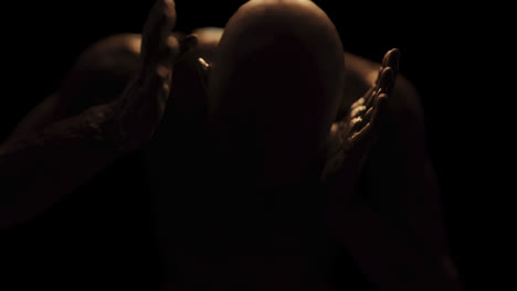 animation of distressed shirtless bald figure holding head in pain in dark room