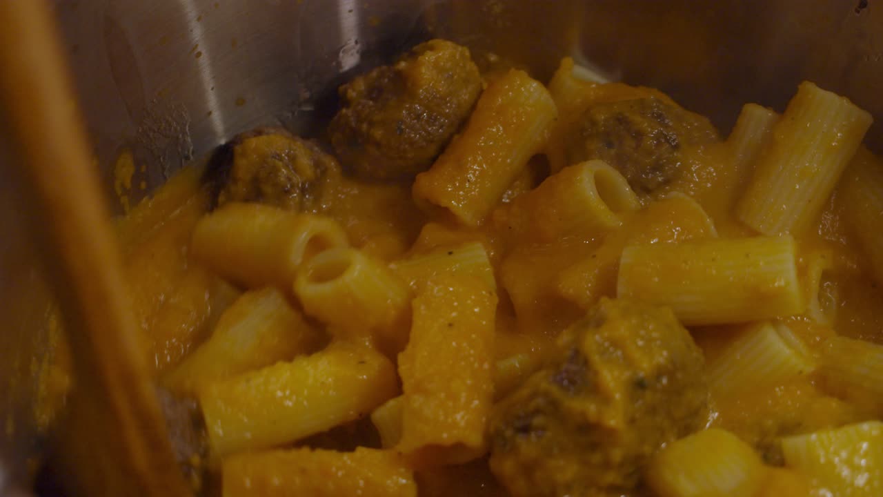 revolviendo y mezclando pasta con salsa de verduras dentro de la olla