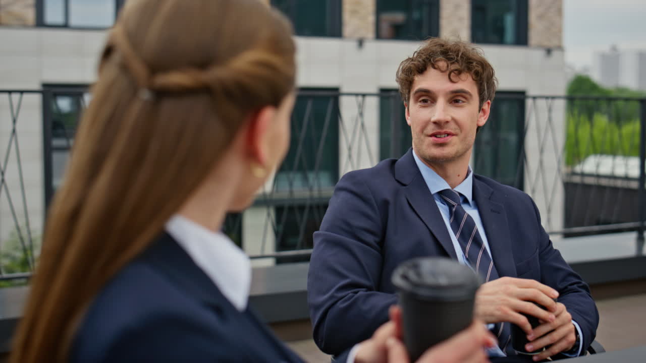 Relaxed businessman businesswoman talking at coffee break on terrace closeup