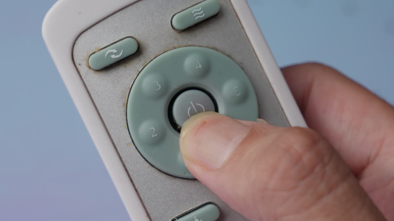 Close-up of a Hand Pressing the Power Button on a Dirty Air Conditioner Remote Control