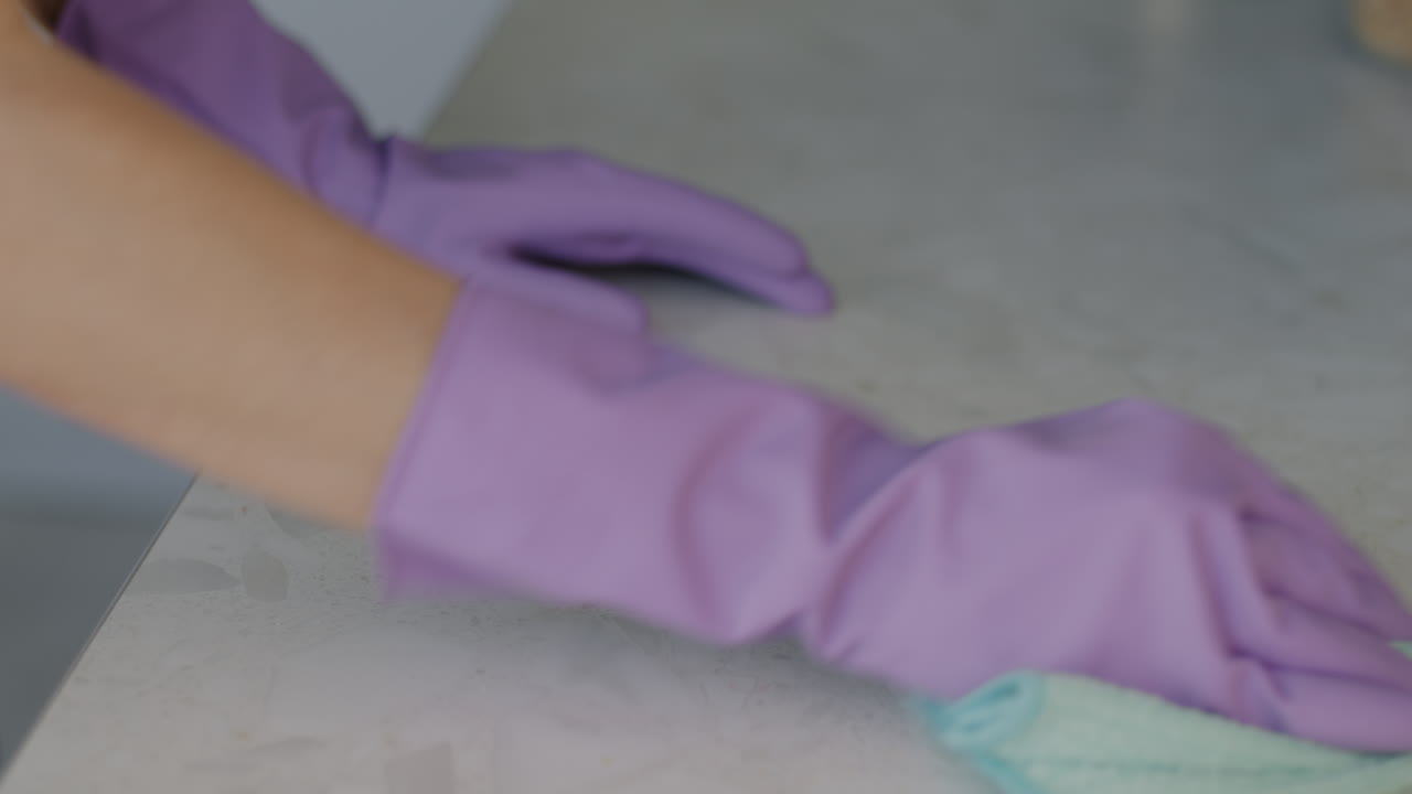 Woman Cleaning Kitchen Countertop with Purple Gloves