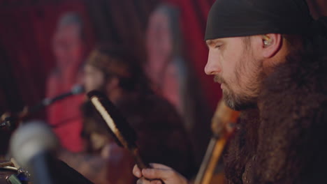 performer taps drums with fur sticks playing ethnic music