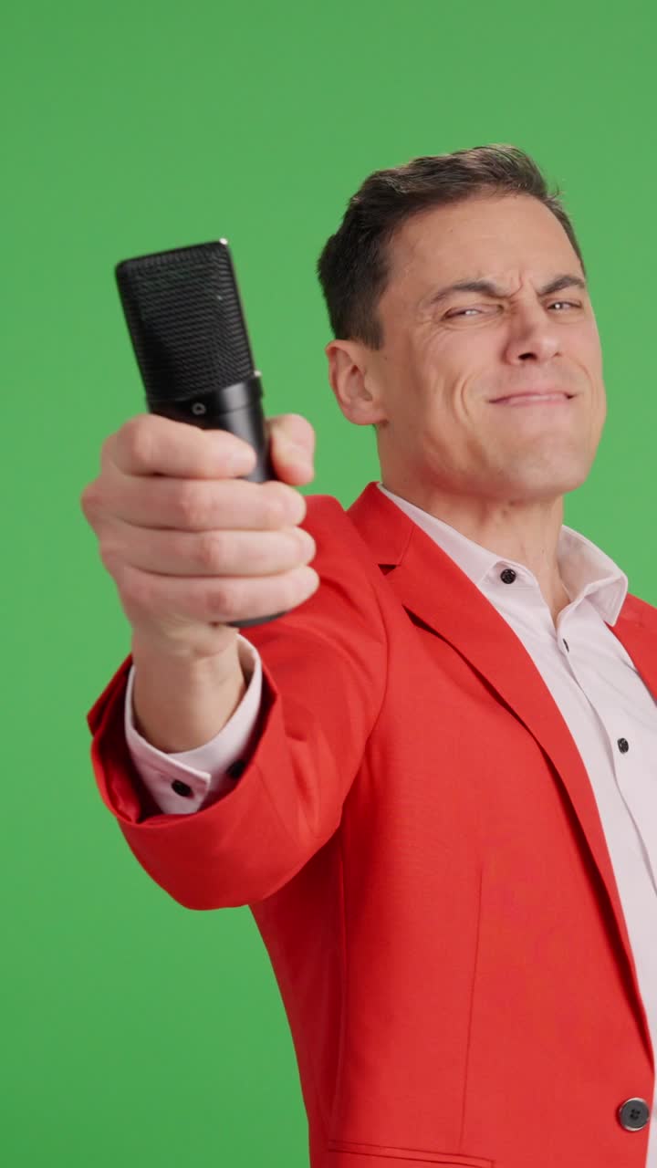 Enthusiastic showman introducing artists with microphone on green screen