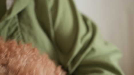 fluffy brown dog looking attentively as owner in green gown gently releases it from hold, capturing heartfelt moment of trust and calmness between pet and caregiver