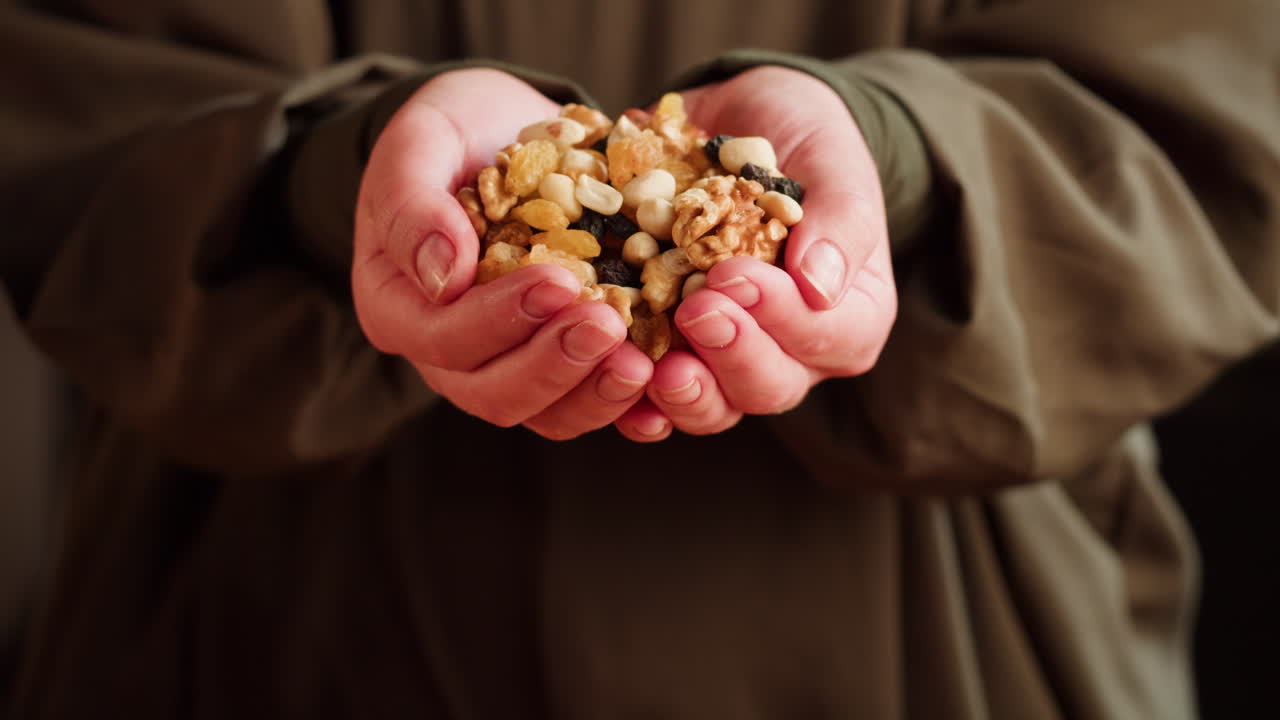 Hands holding and pouring mixed nuts and dried fruits
