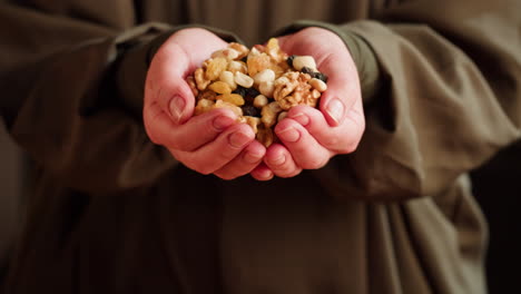 hands holding and pouring mixed nuts and dried fruits