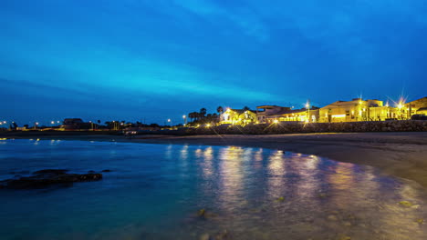 Timelapse-Del-Atardecer-Con-Cielo-Azul-Oscuro-Y-Luces-Reflejantes-De-La-Ciudad-Sobre-Las-Aguas-Costeras.