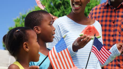 family eating watermelon and holding american flags