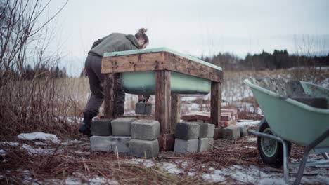 the man is removing bricks from the wheelbarrow and placing them near the diy hot tub - static shot