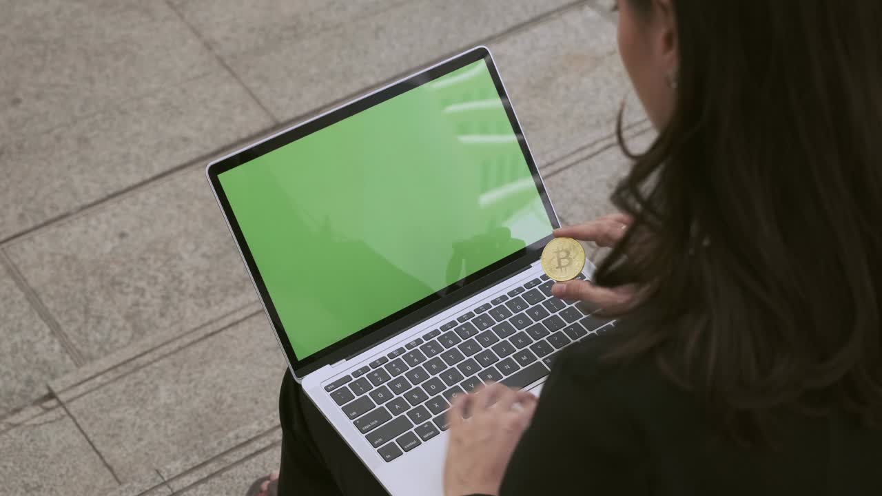 mujer de negocios usando en la computadora portátil con fondo de pantalla verde y mantener bitcoin.