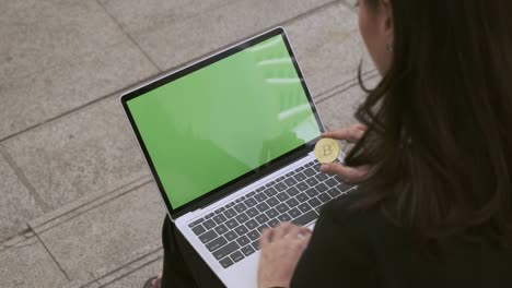 businesswoman using on laptop with green screen background and hold bitcoin.