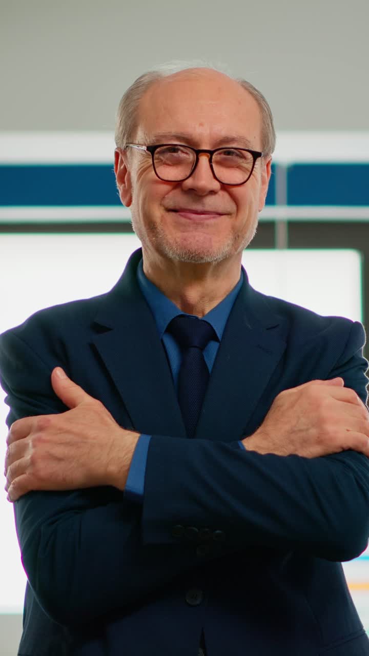 Vertical video Elderly businessman looking at camera crossing arms and smiling