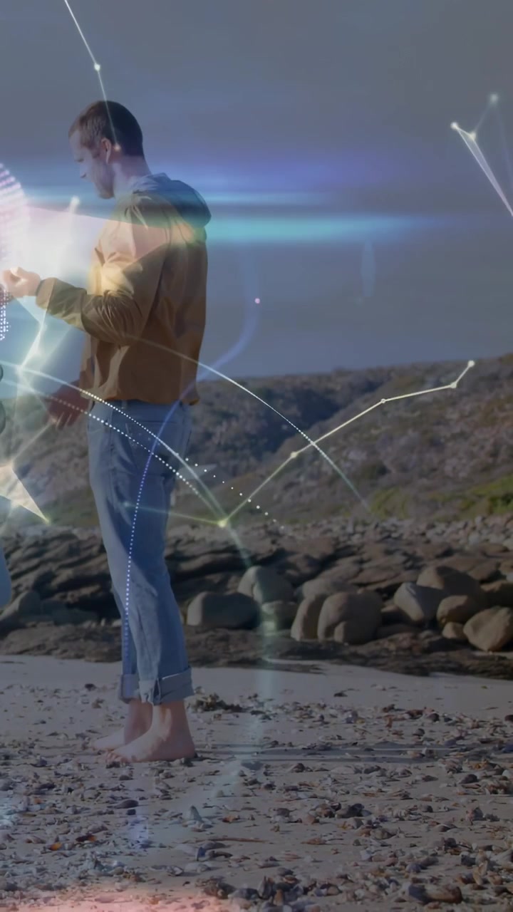 Video verticale: Uomo che tocca il telefono in spiaggia facendo brillare linee olografiche e condividendo un'app tecnologica con la famiglia.