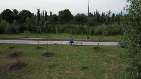 Dolly-out-with-jib-up-above-a-lake-and-natural-area-with-view-of-a-trail-and-a-runner-resting,-in-Xochimilco,-Mexico-City